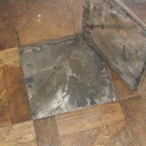 A close up of a loose panel and the uneven tar beneath.